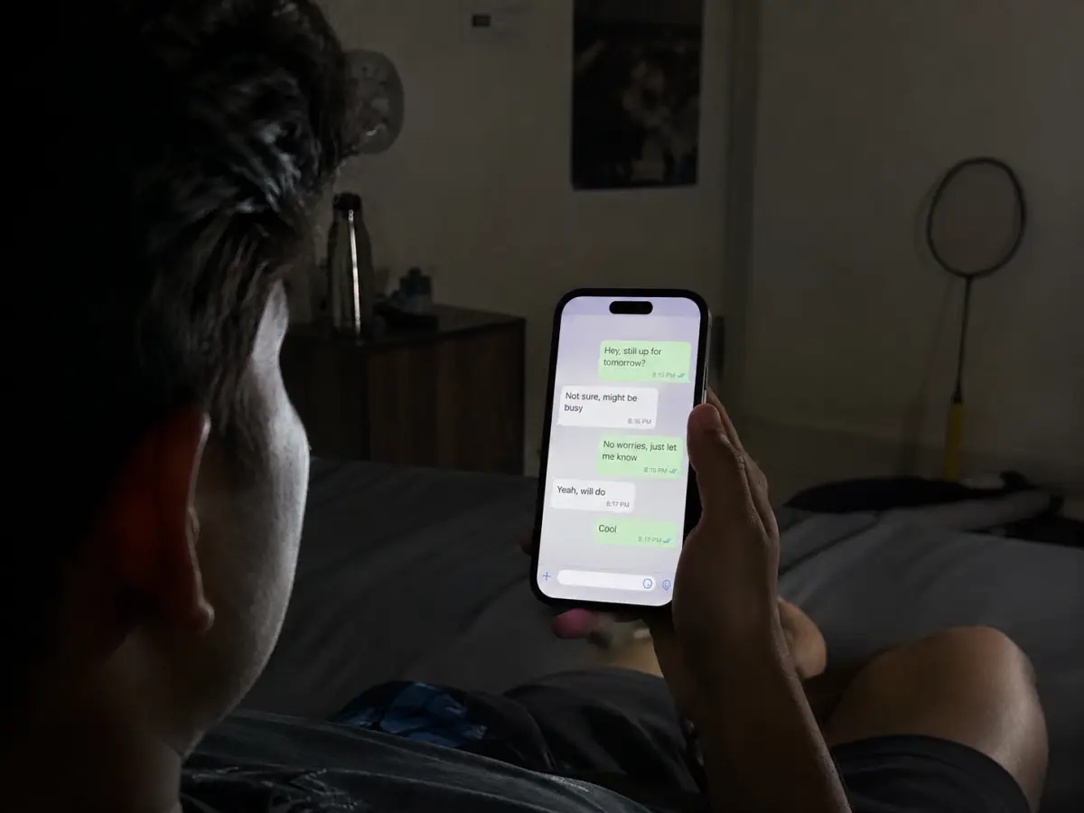 Phone showing a vague badminton group chat, racket leaning against the wall