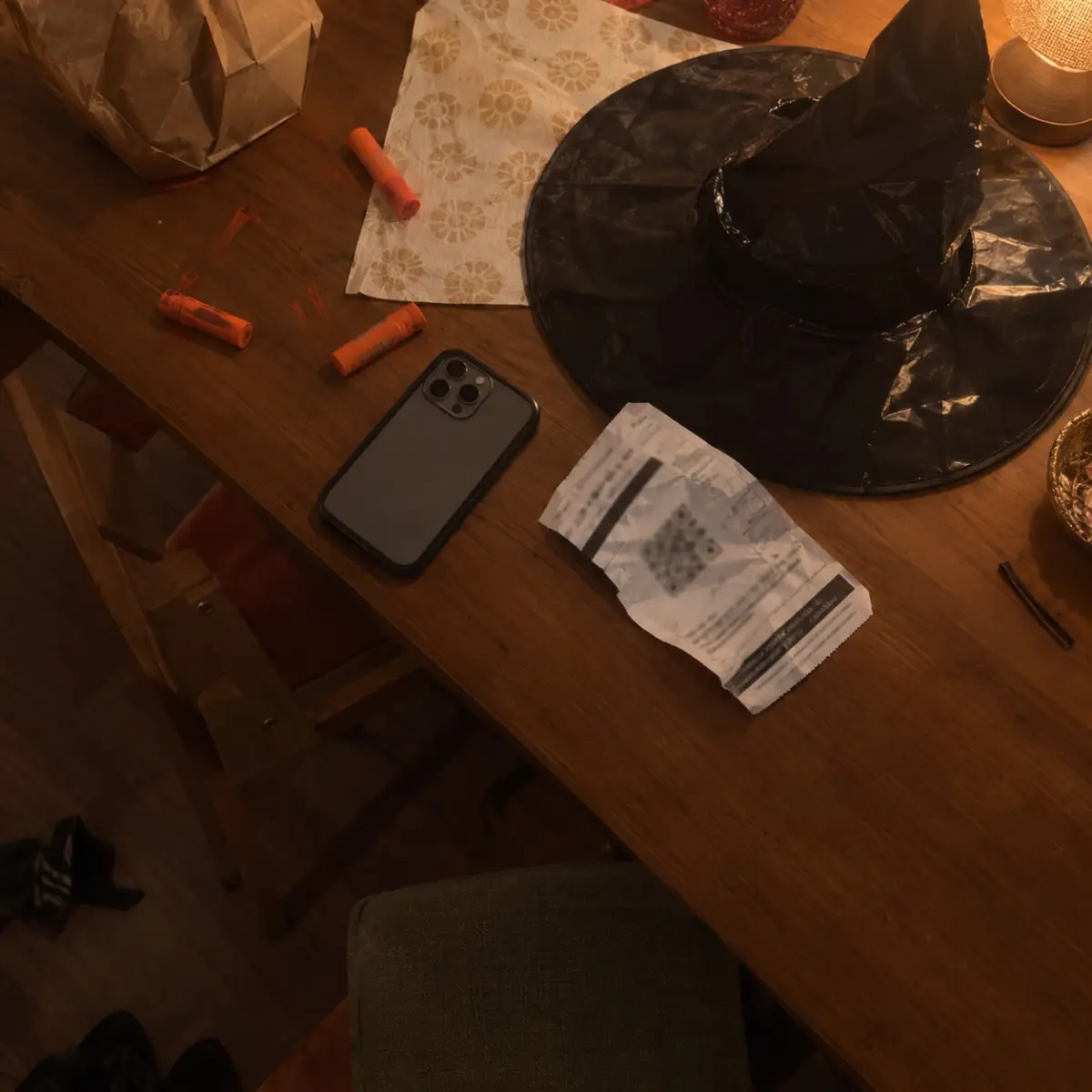 Phone face down on a kitchen table next to Halloween face paint, a ticket stub, and a witch hat