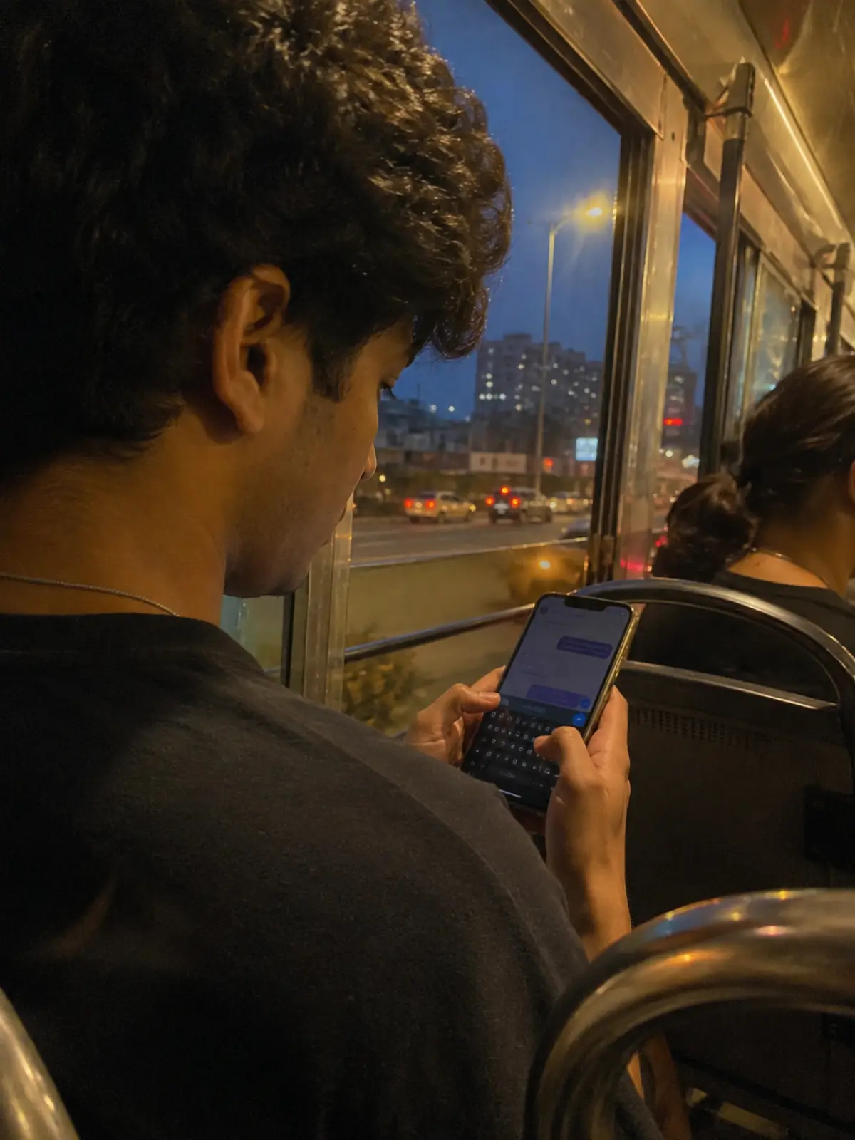 Young professional on an evening commute, thumb hovering over send on a text draft